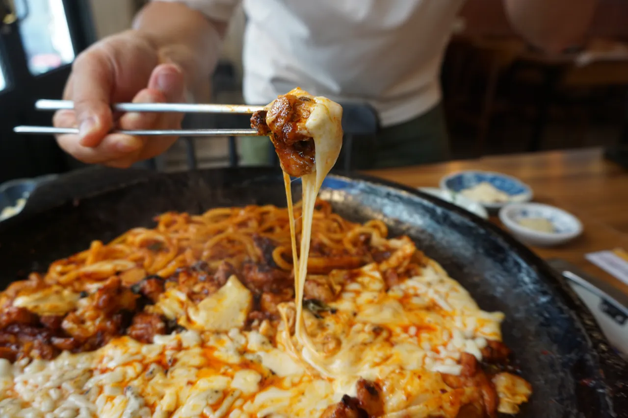논현동 맛집 류몽민 철판에서 녹은 치즈와 직화 닭갈비를 집어 올리는 모습
