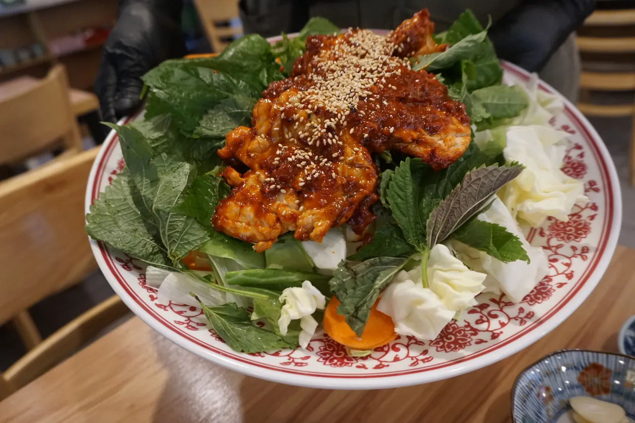 깻잎과 양배추 위에 올린 직화 초벌 닭갈비 한 접시