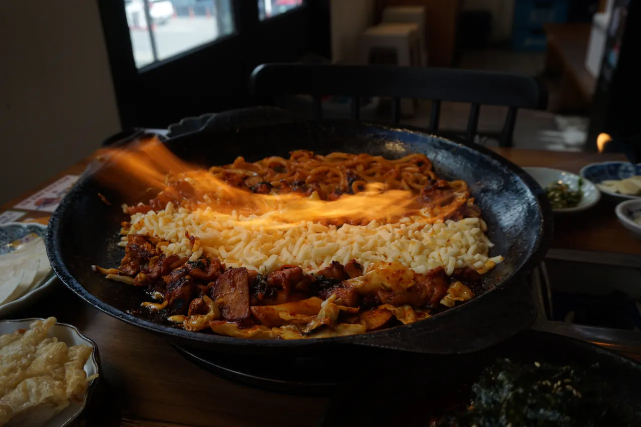 닭갈비 위 모짜렐라 치즈를 토치로 녹이는 모습